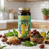 Bottle of 'Honey Herbal Blend Booster' on a kitchen counter with ingredients like dates, leaves, and oil.